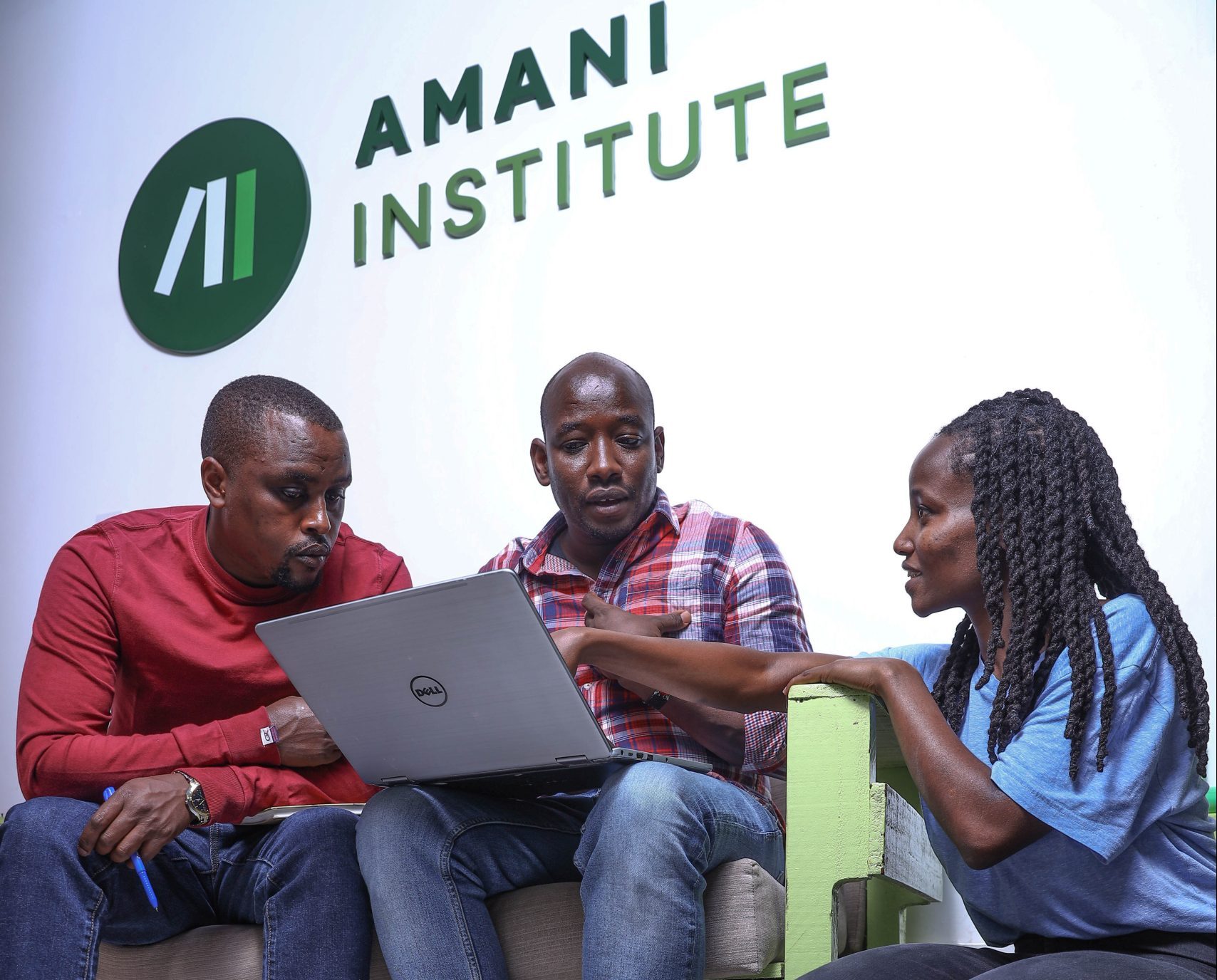 two program participants and a facilitator with the Amani Institute logo in the background
